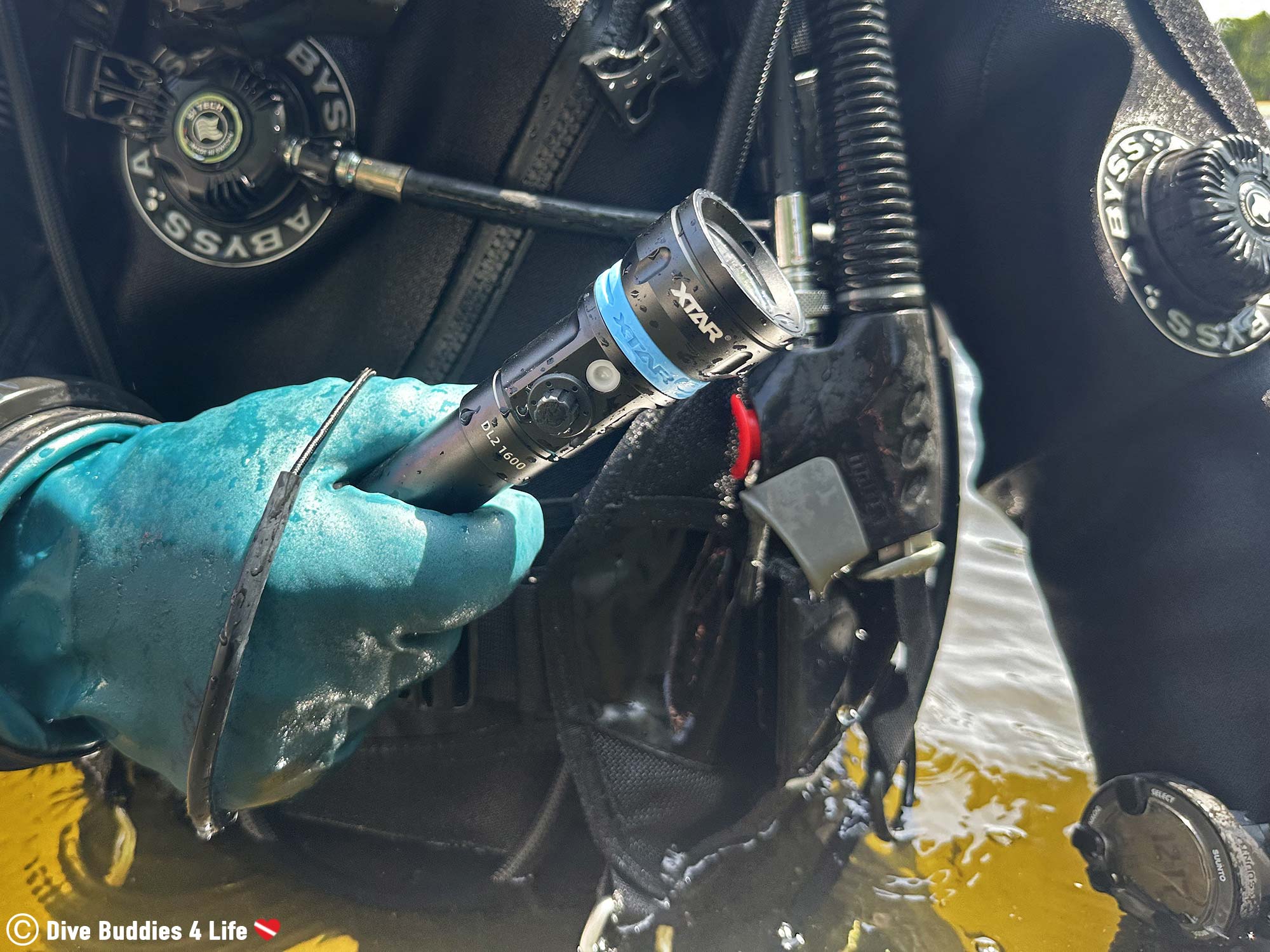 A Diver Fresh Out Of The Water Holding The Xtar UltraPointer Dive Light Against His Scuba Diving Gear