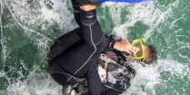 A Woman Diver With A Yellow Scuba Mask Rolling Into The Water With Scuba Diving Gear In Mexico