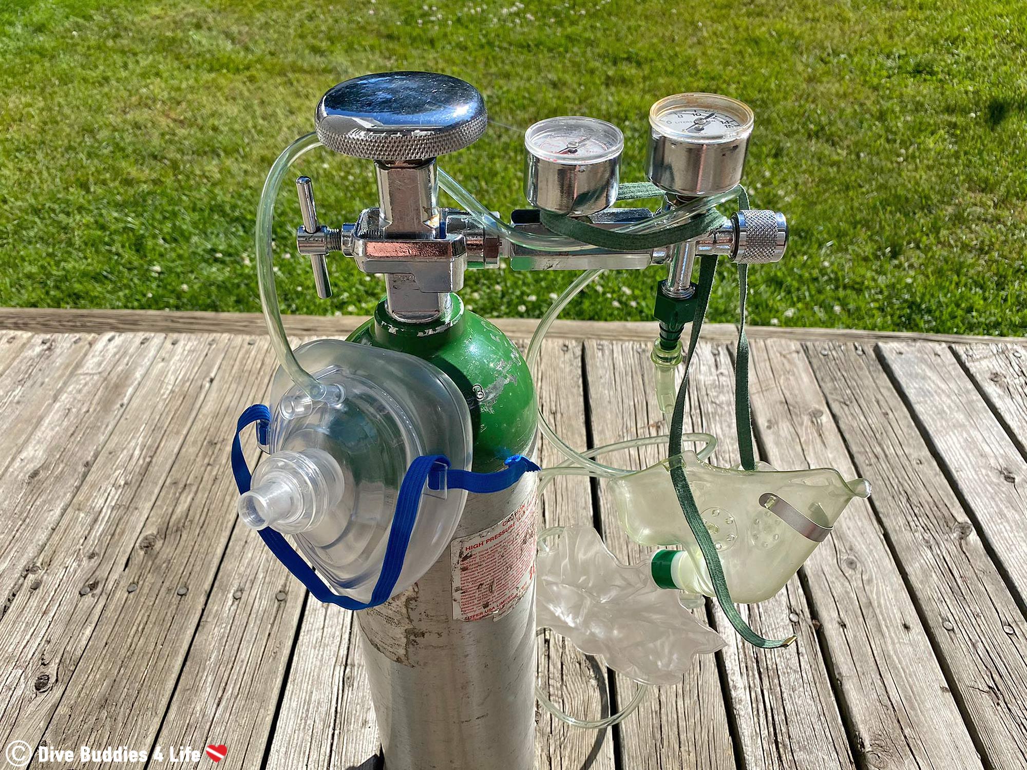 An Oxygen Bottle Standing Up With Two Different Administration Masks Hanging From The Valve, Scuba Diving First Aid