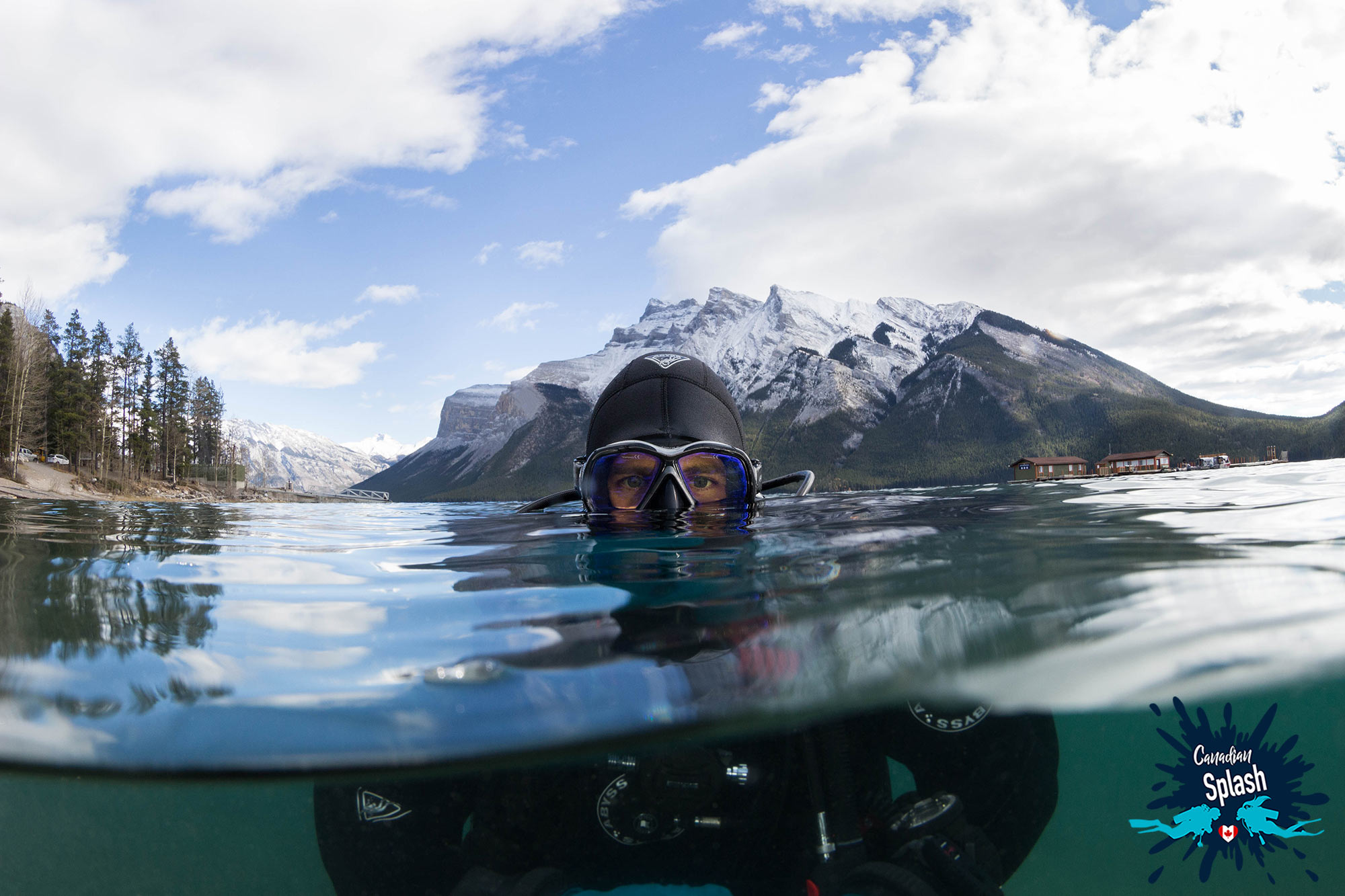 Scuba Diver In Jasper National Park Peaking Out Of The Water With The White Snow Capped Rocky Mountains In The Background, Canadian Underwater Adventures