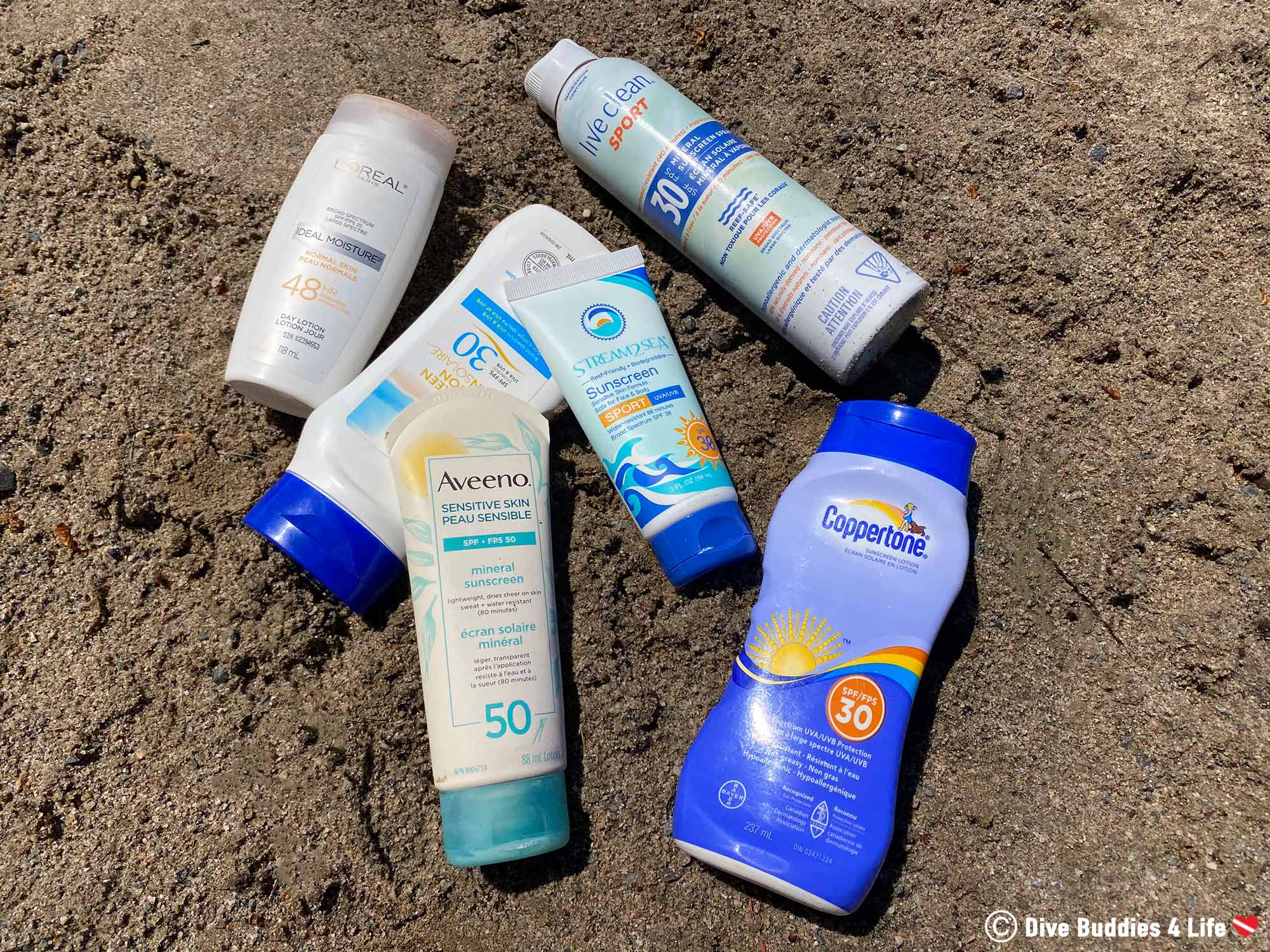 Several Different Bottles Of Sunscreen Laying On The Sand Of A Beach