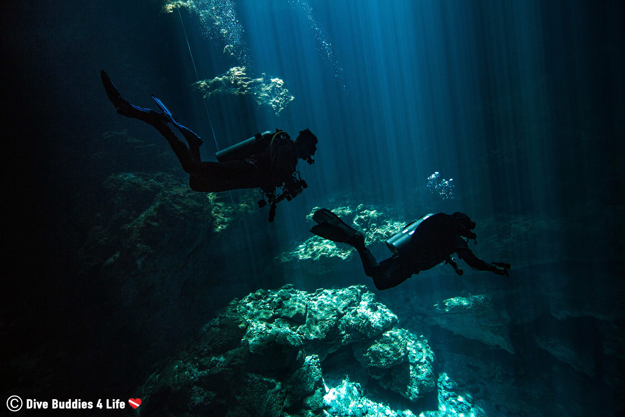The Silhouette Of Two Scuba Divers Descending Into The Underwater Cenotes Called The Pit In Tulum, Mexico